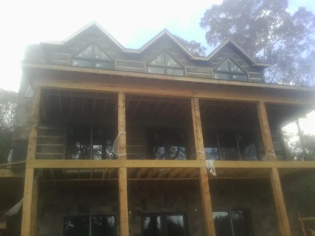 Dormers and porch framing on a large log home under construction — Roof Coating work by our crew in Kirkland