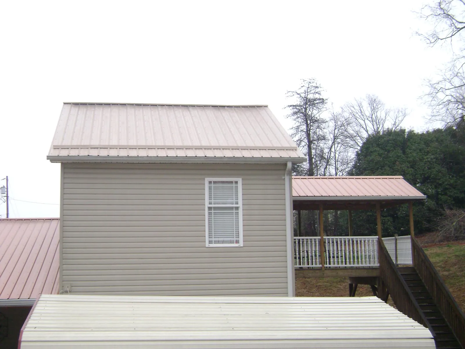 Tan metal roofs on a two story addition and attached porch, from a Roof Replacement job in Kirkland