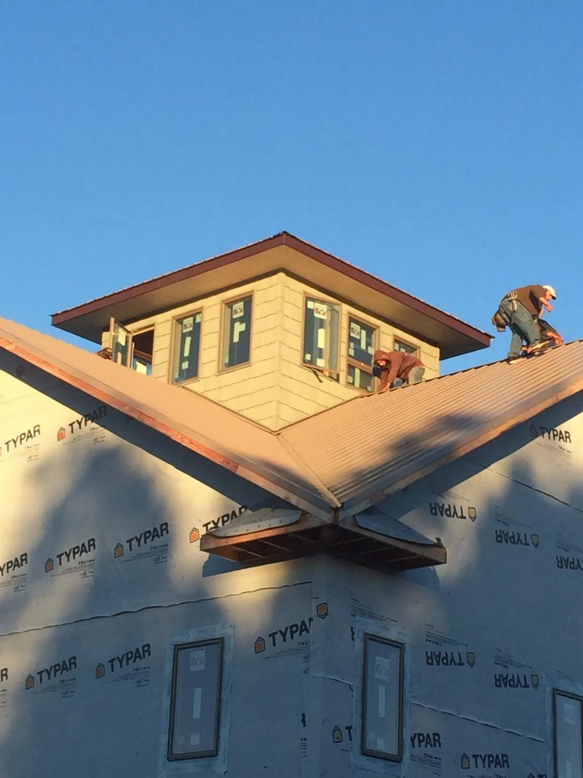 Roofers working around a rooftop cupola on a new metal roof at sunset — Roof Waterproofing in Kirkland by Roofing Brothers